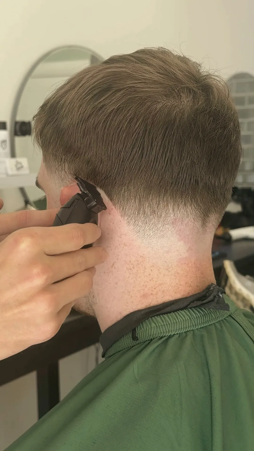 Rab's hand holding clippers at the neckline.
