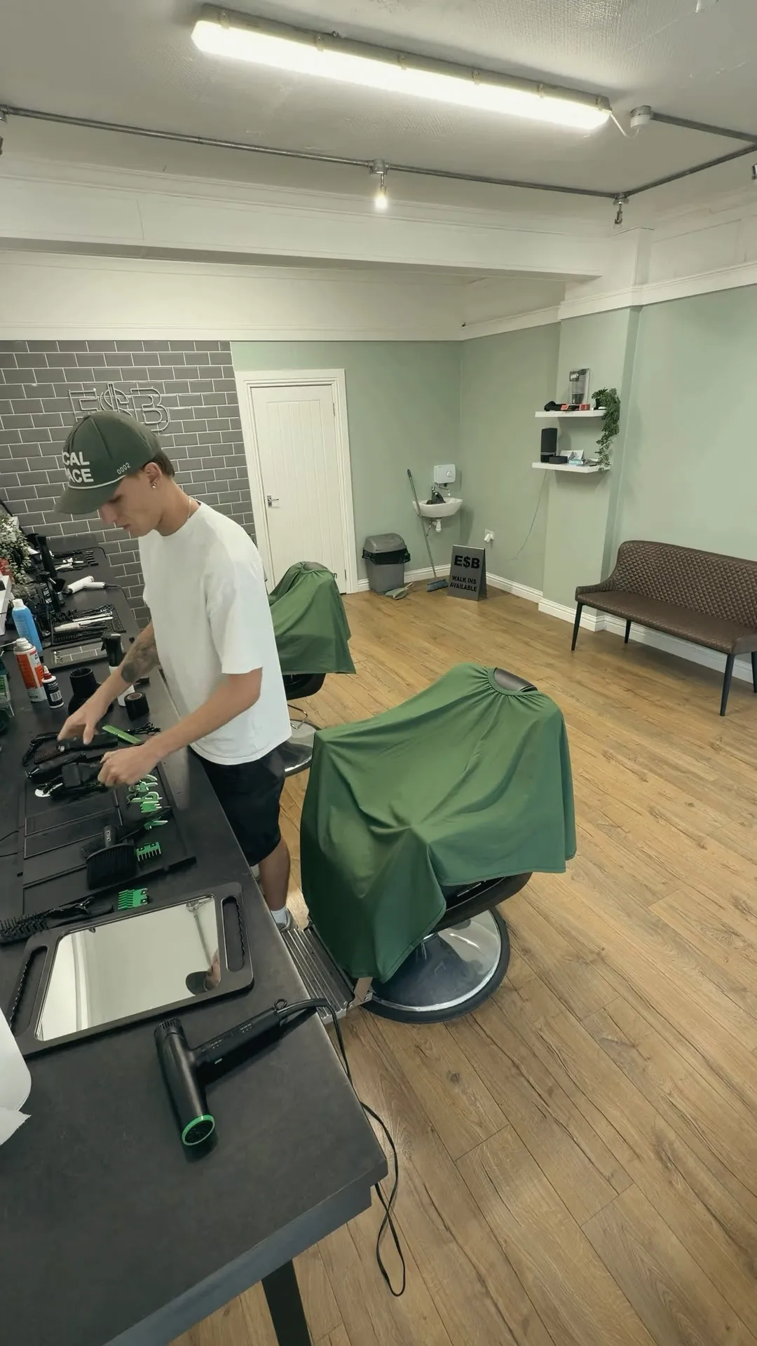 Rab at his station at Escobarber — The Studio, sage walls and green chairs.