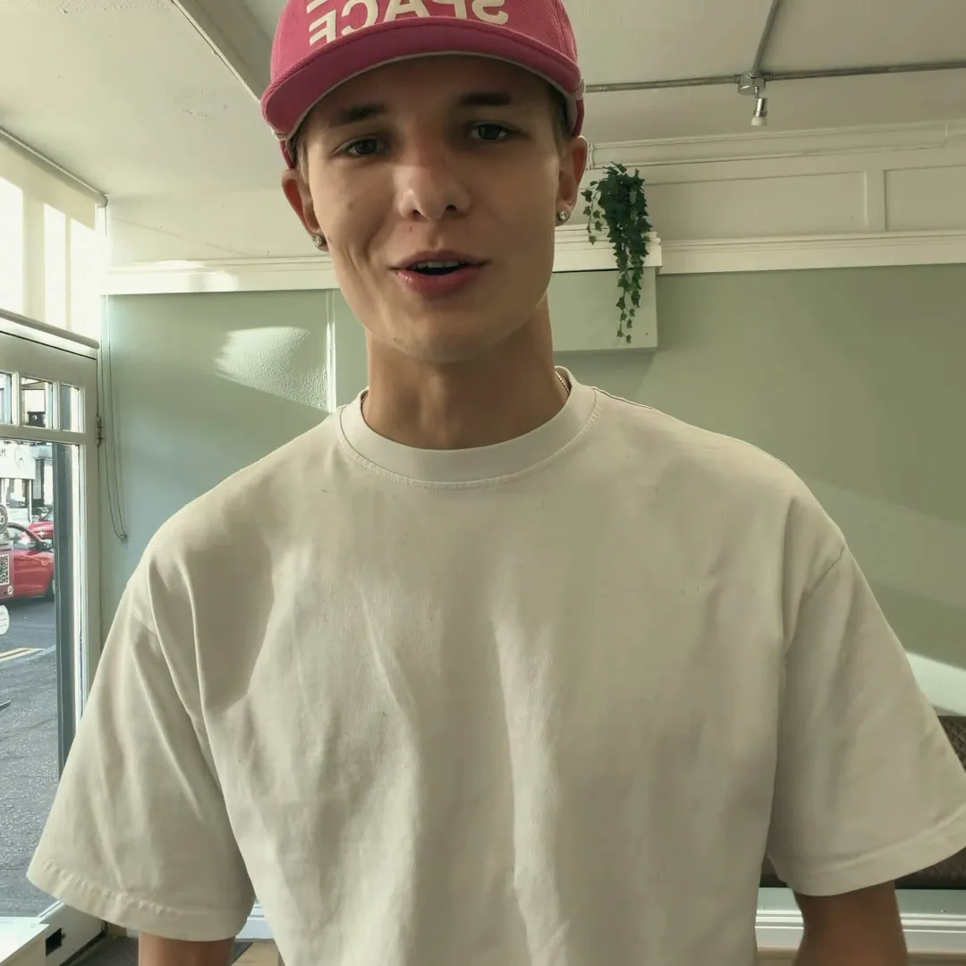 Rab, wearing a pink cap and white tee, looking at the camera.
